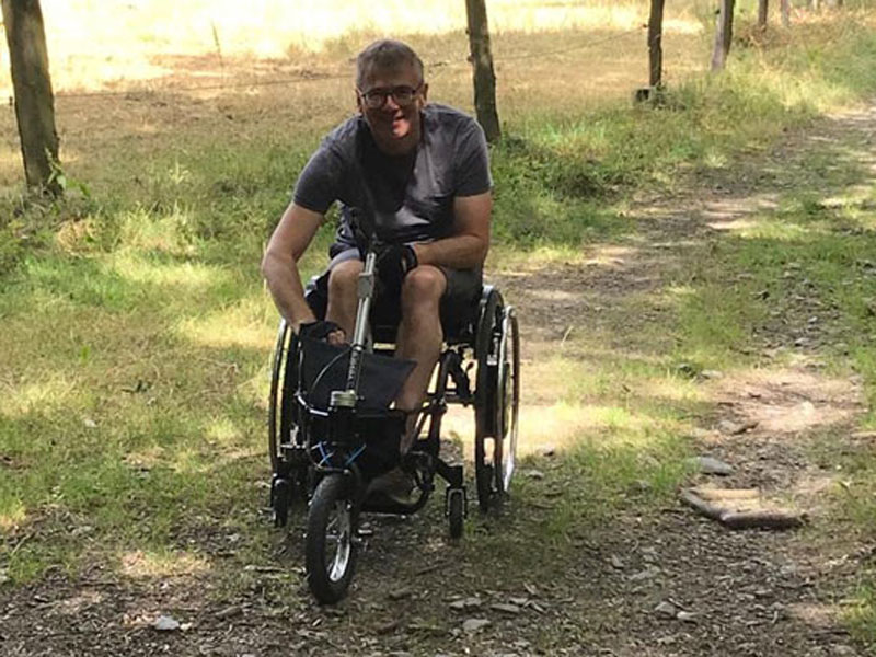 Marc B auf Waldweg mit Vorsatzrad und Rollstuhl